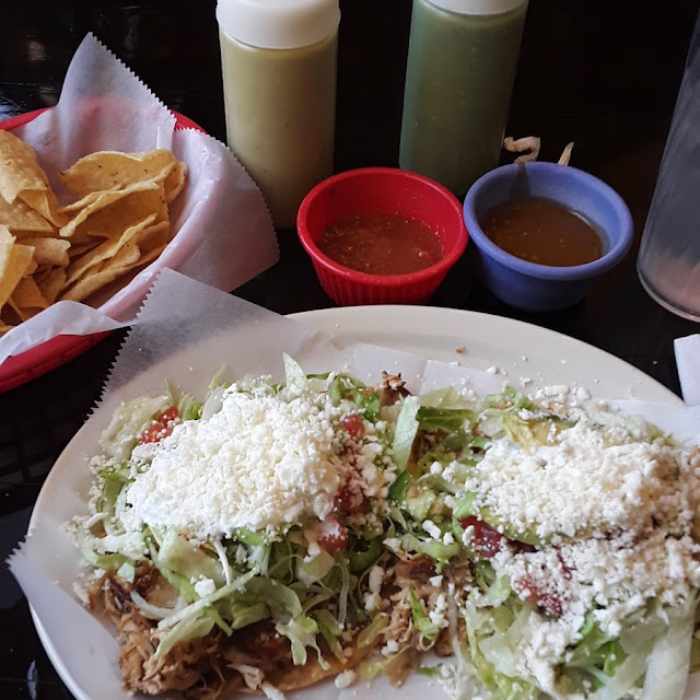 Tostada De Polo Disabrado Comes Cream Goat Cheese Avacado Tomato Lettuce Beans and Shredded Chicken